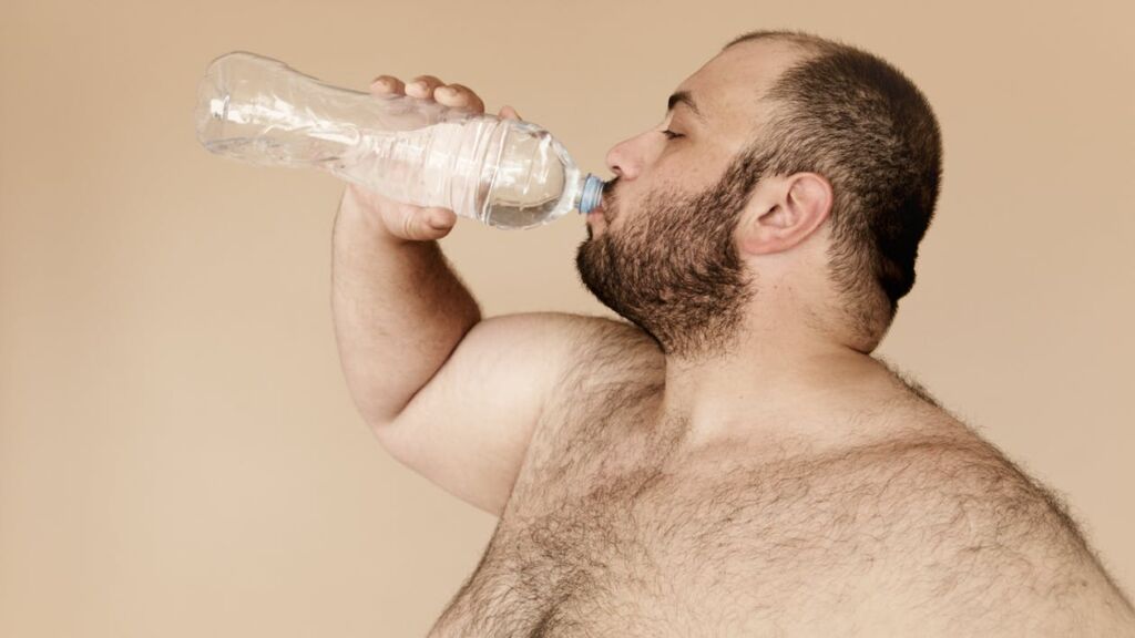Overweight man drinking from a plastic water bottle