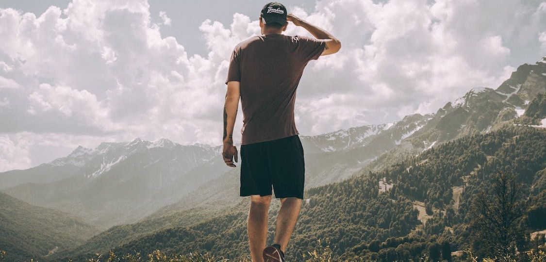 Man shading his eyes while hiking on a bright day