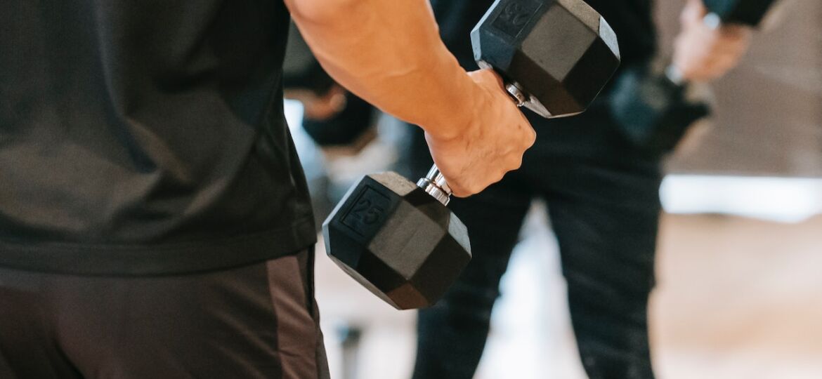 Male in his 40s performing arm curls with hand weights as part of his men's exercise routine.
